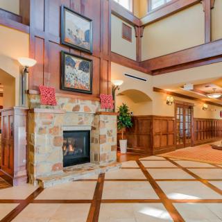 A spacious lobby area featuring a fireplace with stone surround, wooden paneling, and high ceilings.