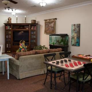 A cozy living room featuring a sofa, television, bookshelf, checkers board game, and an aquarium.