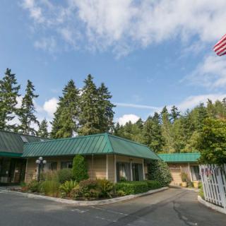 A building with a green roof surrounded by trees and a clear blue sky, featuring an American flag near the entrance.