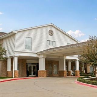The image shows the entrance of a large residential building with a covered driveway.