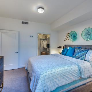 A modern bedroom with stylish decor, featuring a neatly made bed and decorative wall art.