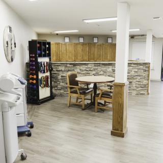 A modern, minimalist room featuring a wine rack and a small table with chairs on a hardwood floor.