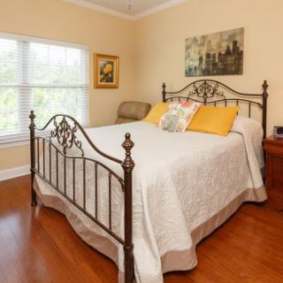A cozy bedroom with an iron bedframe, white bedding, and yellow accent pillows.