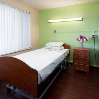 A simple hospital room with a single bed and green walls.