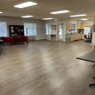 A spacious community center interior with an open floor plan and a kitchen area.