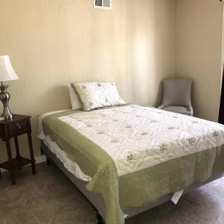 A simple bedroom with a bed, side table, and lamp.