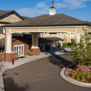 A welcoming entrance to a residential community center, surrounded by lush landscaping and bright skies.
