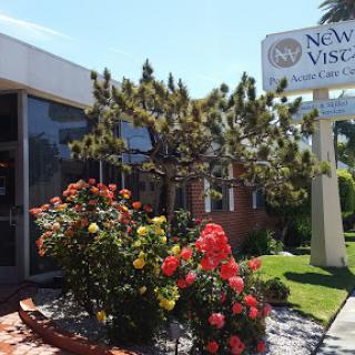 A vibrant view of a landscaped building with a welcoming sign and colorful flowerbeds.