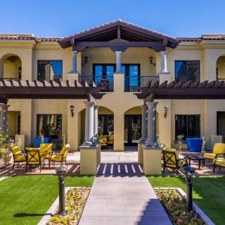 A luxurious two-story house with a well-maintained garden and outdoor patio seating.