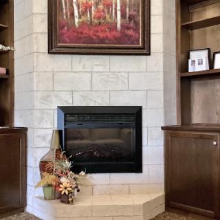 A beautifully decorated living room featuring a modern fireplace, surrounded by elegant shelving and autumn-themed accents.