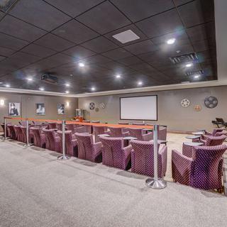 A well-lit theater room with rows of comfortable seating facing a large screen.