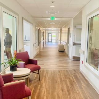 A brightly lit hallway with chairs and large windows.