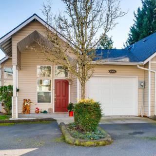 A cozy residential house with a garage and a small front yard featuring a tree.