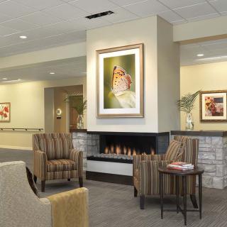 A modern lobby seating area with comfortable chairs, a fireplace, and artwork on the wall.