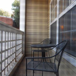 A small urban balcony featuring metal chairs and a table.