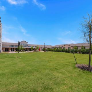 A spacious lawn in front of a large building under a clear blue sky.