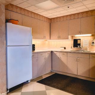 A tidy kitchen corner featuring a refrigerator, countertop, and cabinets.