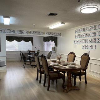 A well-decorated dining room with an elegant table setting and comfortable chairs, featuring wall art and draped curtains.