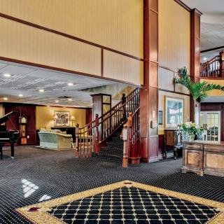 A spacious hotel lobby with a staircase and comfortable seating.