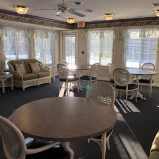 A cozy lounge area featuring comfortable seating and tables, illuminated by natural sunlight.