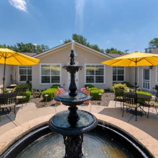 A serene courtyard with a fountain and outdoor seating under yellow umbrellas.