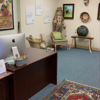 A cozy office space featuring a wooden desk, an Apple computer, and decorative art pieces.