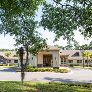 A view of a modern building entrance surrounded by trees and landscaping.
