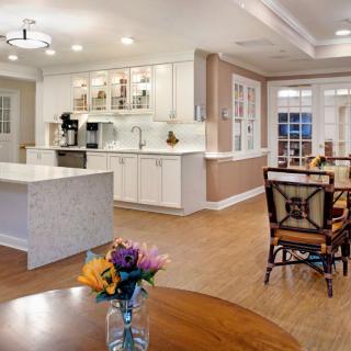 A modern open-concept kitchen and dining area with white cabinets, a large kitchen island, and hardwood floors.
