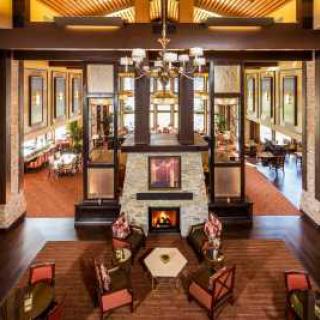 A cozy hotel lobby featuring a central fireplace, surrounded by comfortable chairs and elegant interior design.