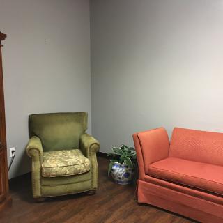 A cozy living room corner featuring a green armchair and an orange sofa.