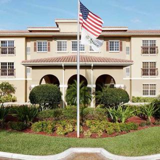 A building with an American flag in front, surrounded by well-maintained greenery.