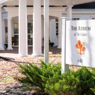 The entrance to a building with a sign that reads 'The Atrium at The Cedars'.