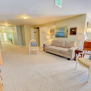 A cozy indoor living space featuring a sofa, chairs, and decorative elements in a well-lit hallway.