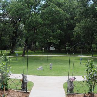 A serene garden view with a pathway leading through lush greenery and trees.