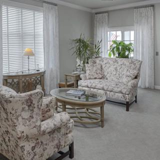 A cozy living room with floral-patterned furniture and natural light.