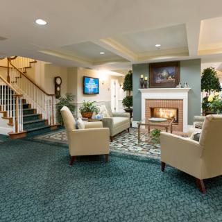 A cozy living room with a fireplace, comfortable seating, and decorative plants.
