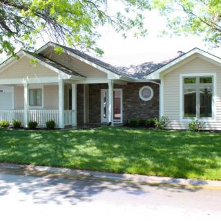 A charming suburban house with a well-maintained lawn and surrounding trees.