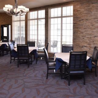 A spacious dining area featuring modern tables and chairs, illuminated by natural light from large windows.
