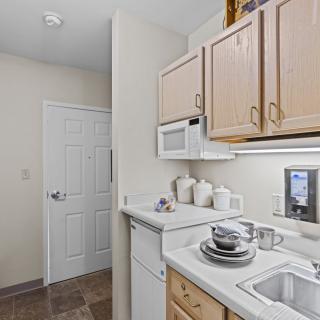A small apartment kitchen with light-colored cabinets and essential appliances.