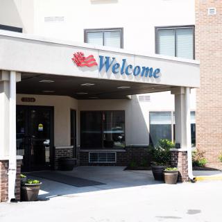 The entrance of a building with a welcome sign and potted plants.