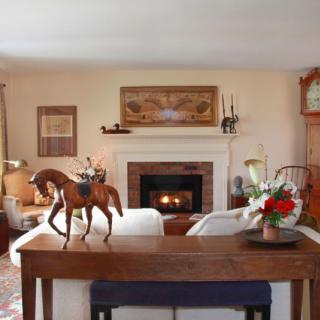 A cozy living room with a fireplace, elegant decor, and a wooden horse sculpture on the table.