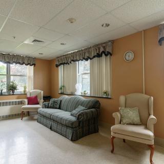 A cozy living room with a sofa, armchair, and windows adorned with curtains.
