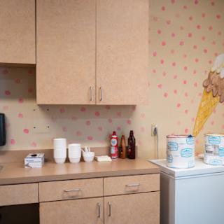 A cozy kitchen corner featuring light wood cabinets, various utensils, and playful wallpaper.
