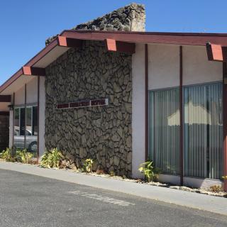 A mid-century modern building with a stone facade and large windows under a clear blue sky.