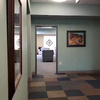 A view down a hallway in an office with artwork on the walls and patterned flooring.
