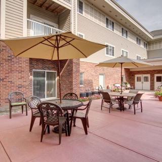 Outdoor patio area with tables and umbrellas in front of a building.