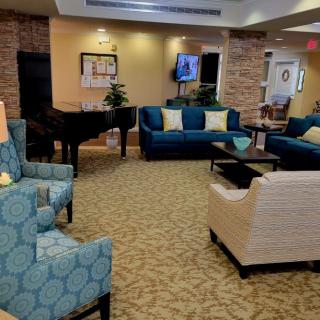 A comfortable lounge area with sofas, armchairs, a piano, and a television.