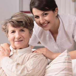 A caregiver smiling with an elderly person in a home setting.
