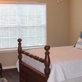 A cozy bedroom with a wooden bed frame and a window with blinds.