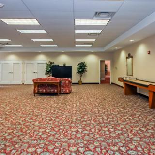 A spacious lounge area with comfortable seating, a television, and decorative plants.